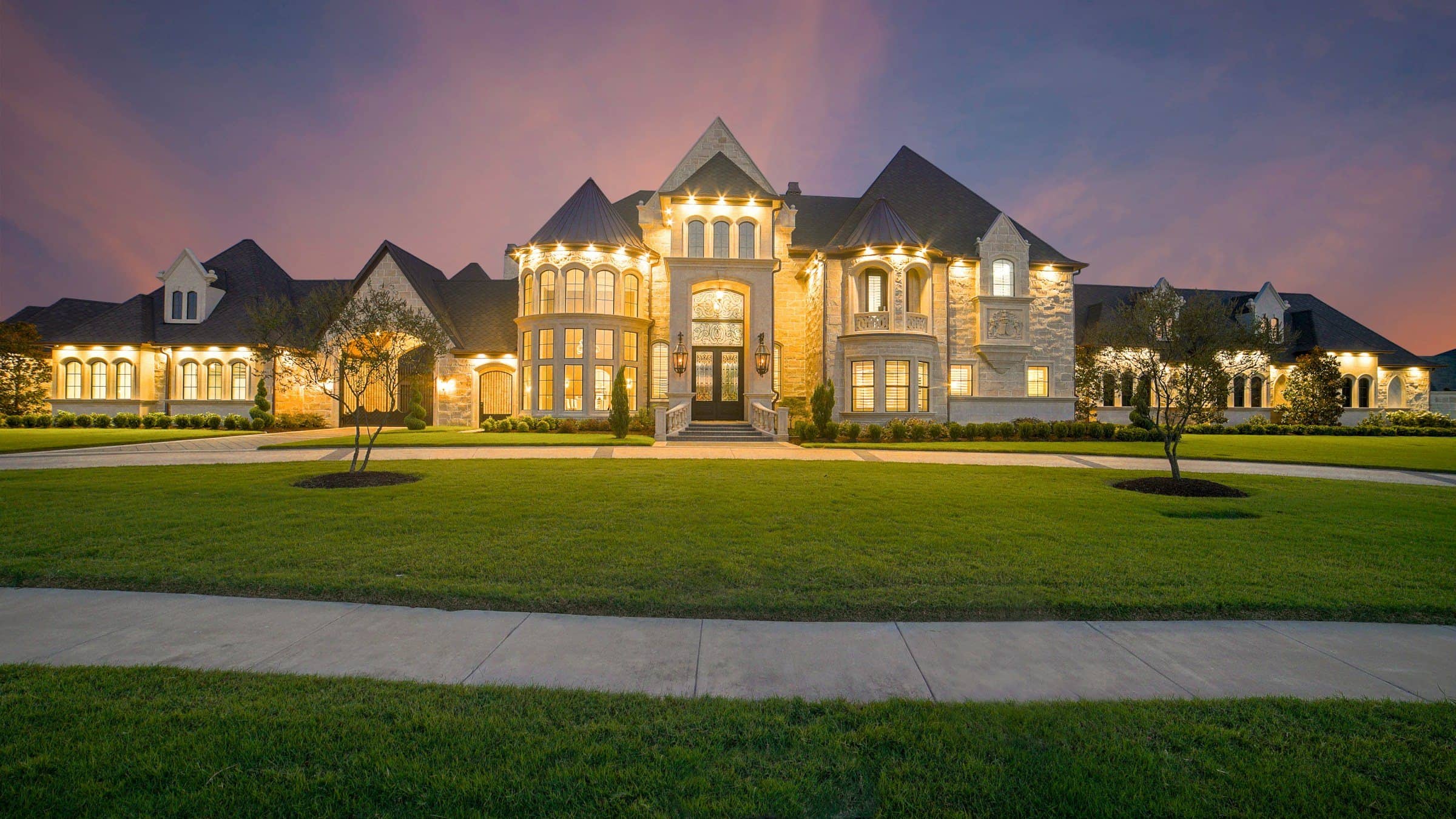 Stately estate home with illuminated windows at twilight