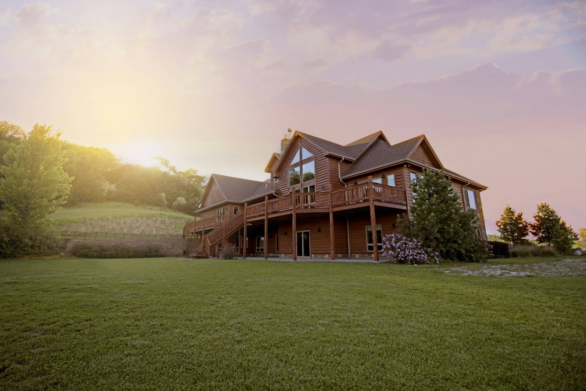 Timber lodge vacation home on a grassy hillside at sunset